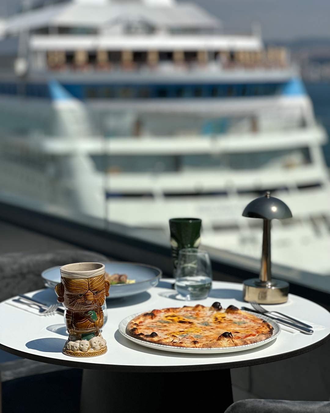 Loi Bosphorus - pizza served on a terrace table in front of a cruise ship docked at Galataport